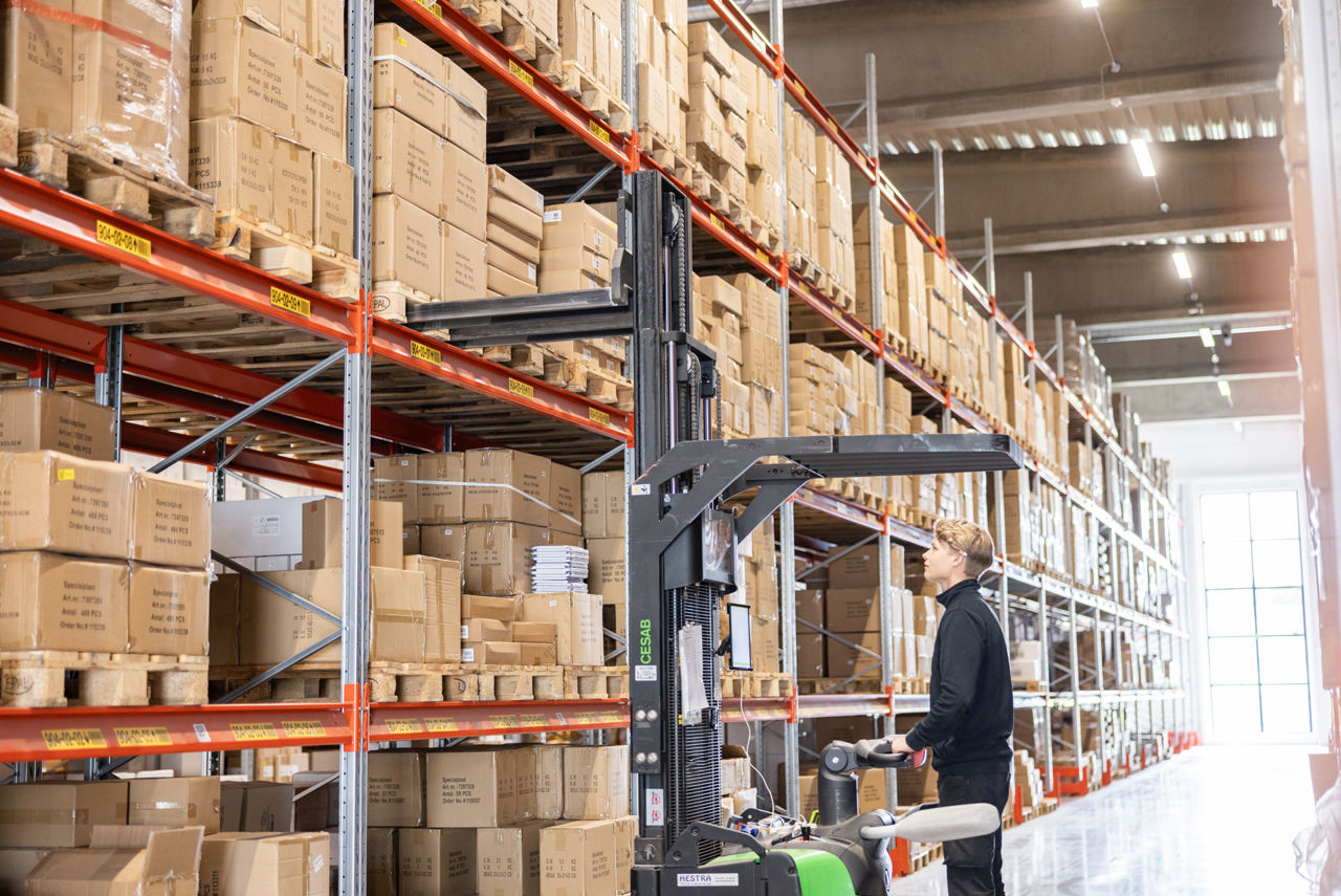Person with a forklift loading stock in a warehouse.
